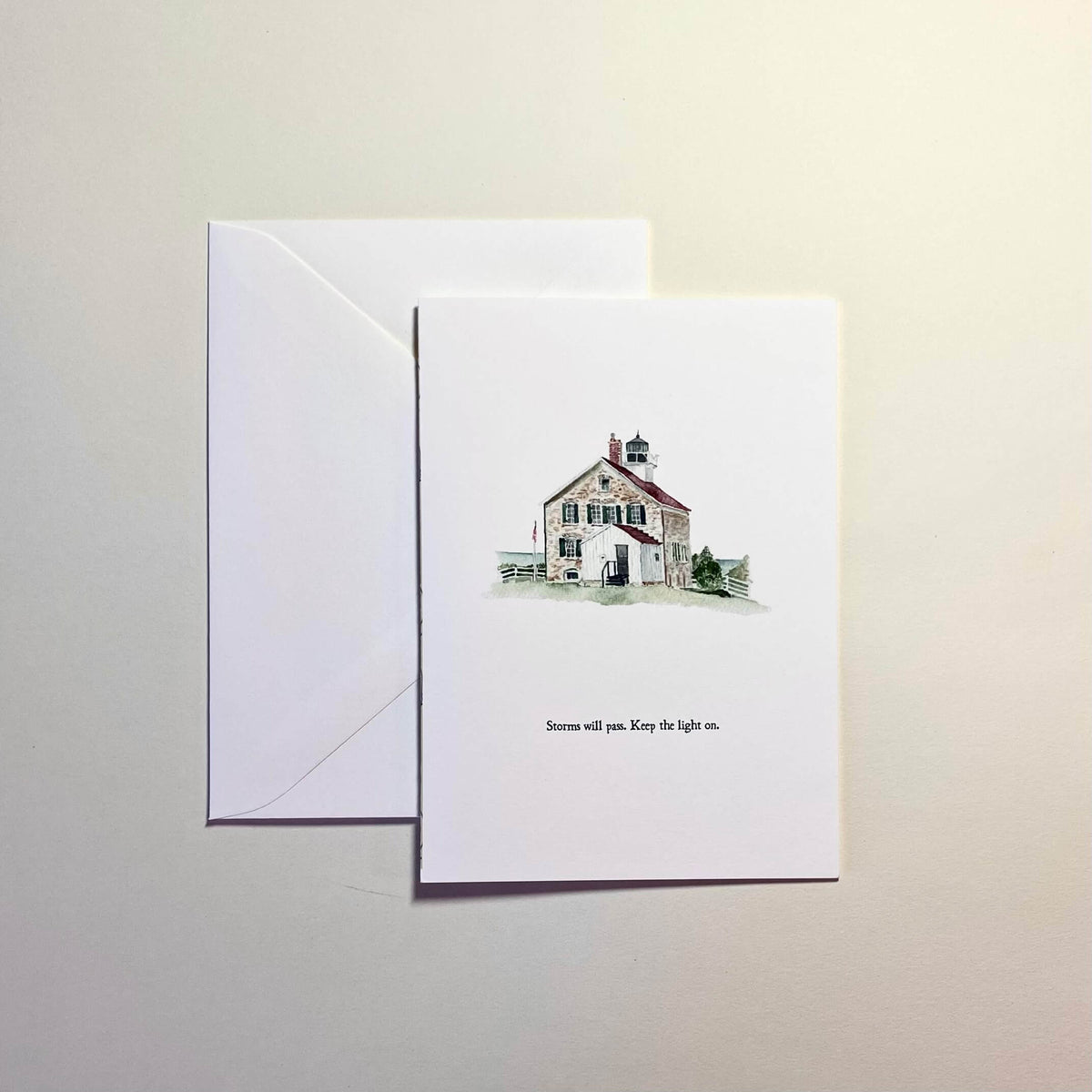 Greeting card with a lighthouse watercolor illustration and envelope on a light background